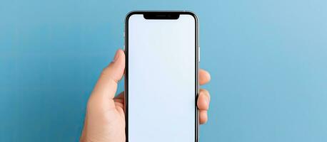 Middle aged man with grey hair using a big phone to check a new mobile app on a blue background with empty white screen and space for advertising photo
