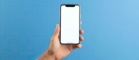 Middle aged man with grey hair using a big phone to check a new mobile app on a blue background with empty white screen and space for advertising photo