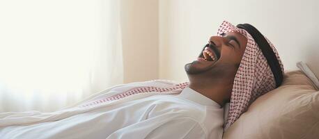 un árabe hombre bien descansado despertar arriba sonriente y disfrutando un agradable Mañana en cama foto