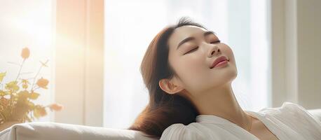 Asian girl relaxing on sofa at home enjoying fresh air photo