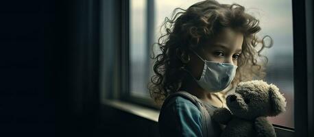 Sick child with protective mask sadly looking out the window photo