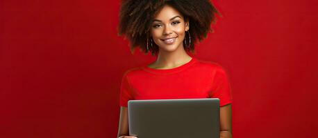 Smiling young African American girl with laptop on red wall background studio portrait People lifestyle concept Mock up copy space photo