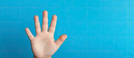 Portrait of a five year old boy displaying five fingers on a blue background with empty space photo