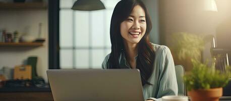 Asian woman happily using laptop at home photo