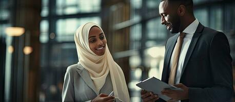 africano americano hombre negociaciones a musulmán mujer de negocios en moderno oficina participación documentos foto