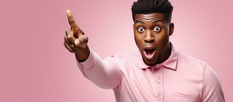 Astonished African American man pointing at empty space expressing surprise and excitement while advertising on pink isolated background photo