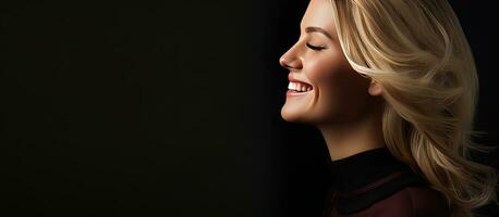Blond woman in sweater smiling against dark background side view photo