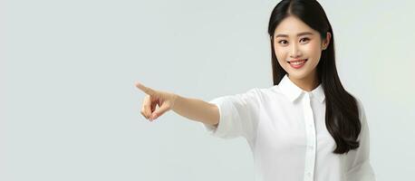 Smiling Asian woman in white shirt pointing to empty space photo