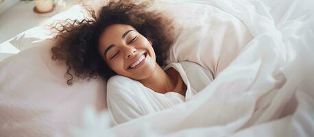 Happy African girl on a bed with copy space laughing and playing with a blanket while looking at the camera photo