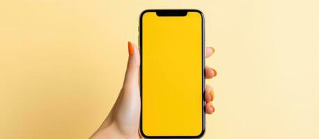 Caucasian girl pointing at empty smartphone screen in a yellow studio photo