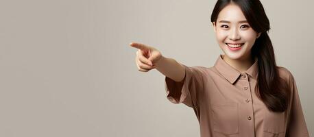 Asian woman in brown shirt with a smile pointing to blank space for advertising photo