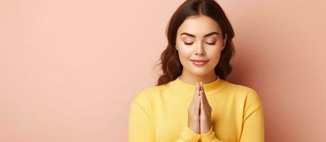 Brunette girl in yellow sweater relaxing and meditating with eyes closed isolated on pastel pink background photo