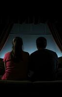 Young couple sitting on sofa watching TV together at home photo