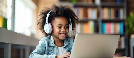 African American girl studying online at home with headphones and a laptop photo