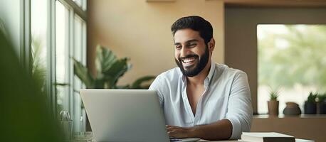 Happy Arab freelancer working from home smiling at laptop screen photo