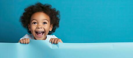 Child laughing behind blank blue paper for ad photo