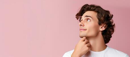 Young white man on pink background holds space on hand amazed and happy photo