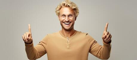 Blond man joyfully pointing with both hands towards an object photo