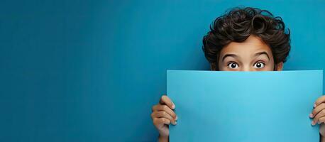 sorprendido adolescente señalando a azul papel con espacio para un anuncio foto