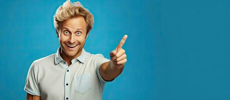 A cheerful and happy adult man with blond hair pointing upwards towards empty space photo