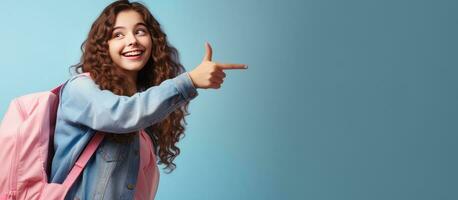 Teenage girl student with books and backpack smiling and pointing at pink ad with space photo