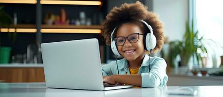 African American girl studying online at home with headphones and a laptop photo