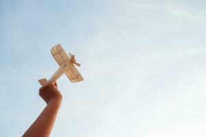 contento niños jugando un de madera juguete avión en el puesta de sol cielo antecedentes. foto