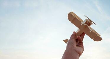 Freedom concept, human hand holding wooden plane on the sunset sky background photo