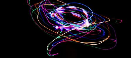 Multi color light painting photography, swirl and curve of blue, green and red light against a black background. photo