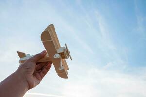 Freedom concept, human hand holding wooden plane on the sunset sky background photo