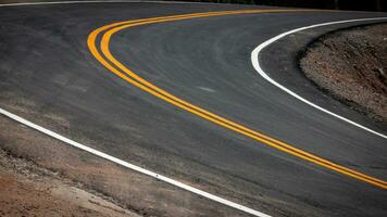el asfalto la carretera tiene amarillo y blanco tráfico líneas cruce el montañas. foto