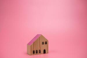 Wood house model on pink background , managing property investment concept, banner background photo