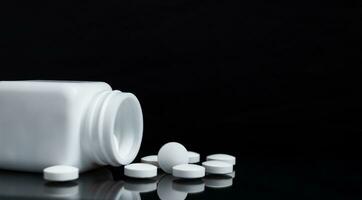 White pills and medicine bottles on black background. photo