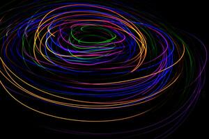 Multi color light painting photography, swirl and curve of blue, green and red light against a black background. photo