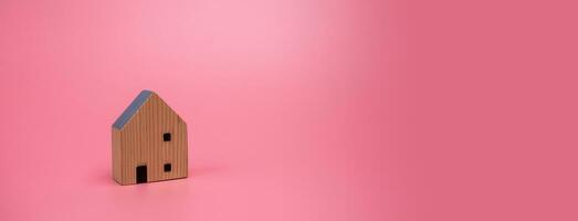 Wood house model on pink background , managing property investment concept, banner background photo