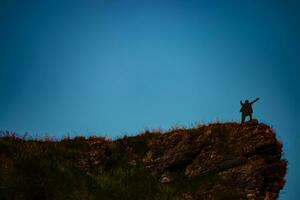 silhouette of man on mountain top over sky and sun light background,business, success, leadership, achievement and people concept photo