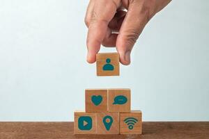 Hand of male putting wood cube block with social media on wooden table. Social media concept photo