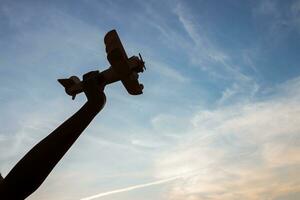 Silhouette of happy children playing a wooden toy plane on the sunset sky background. photo