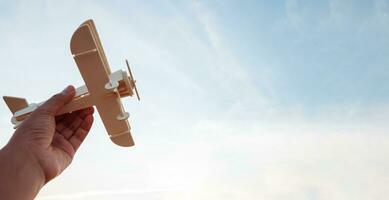 Freedom concept, human hand holding wooden plane on the sunset sky background photo