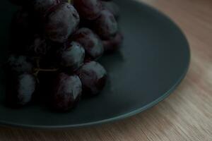 Close-up of grapes with water droplets on a black ceramic plate. photo