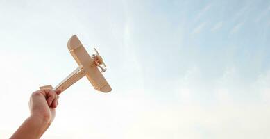 Freedom concept, human hand holding wooden plane on the sunset sky background photo