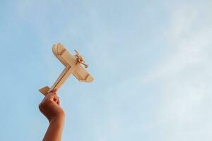 contento niños jugando un de madera juguete avión en el puesta de sol cielo antecedentes. foto