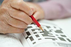 asiático mayor mujer jugando sudoku rompecabezas juego a práctica cerebro formación para demencia prevención, Alzheimer enfermedad. foto