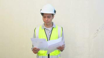 Indonesian worker wear vest and white helmet check report then feel disappointed.  The footage is suitable to use for engineer and safety content media. video