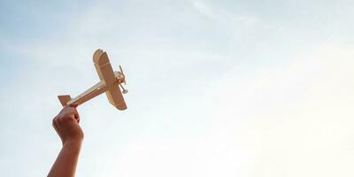 Happy children playing a wooden toy plane On the sunset sky background. photo