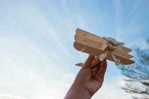 Freedom concept, human hand holding wooden plane on the sunset sky background photo