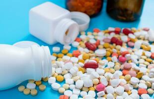 médico pastillas y tabletas derramar fuera de un fármaco botella en azul antecedentes foto