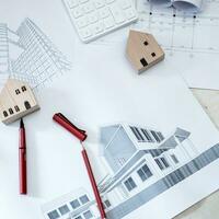 Paper rolls, construction drawings, calculators and wooden house models on concrete floors. photo