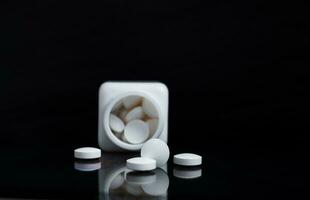 White pills and medicine bottles on black background. photo