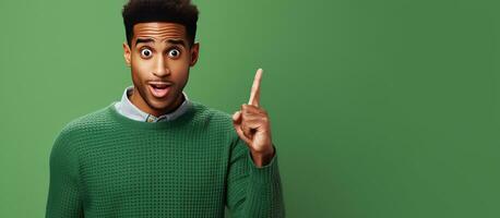 Surprised African American millennial man and casual woman pointing finger on blank space isolated on green background Positive reaction to news emotions photo